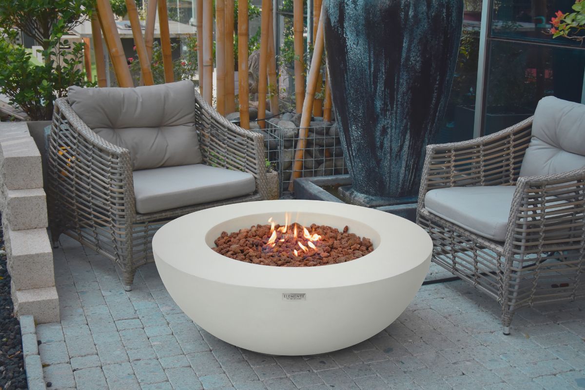 Palenisko LUNAR BOWL Cream White w ogrodzie z wiklinowymi fotelami